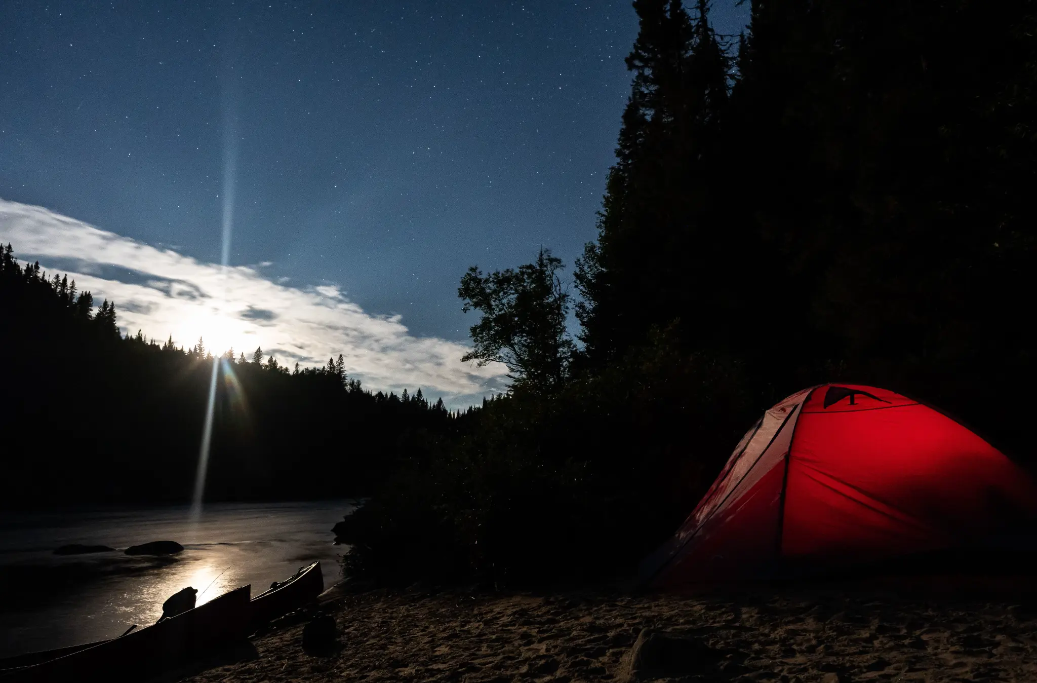 Tente rouge illuminée au bord de la rivière sous les étoiles — Haute-Gatineau